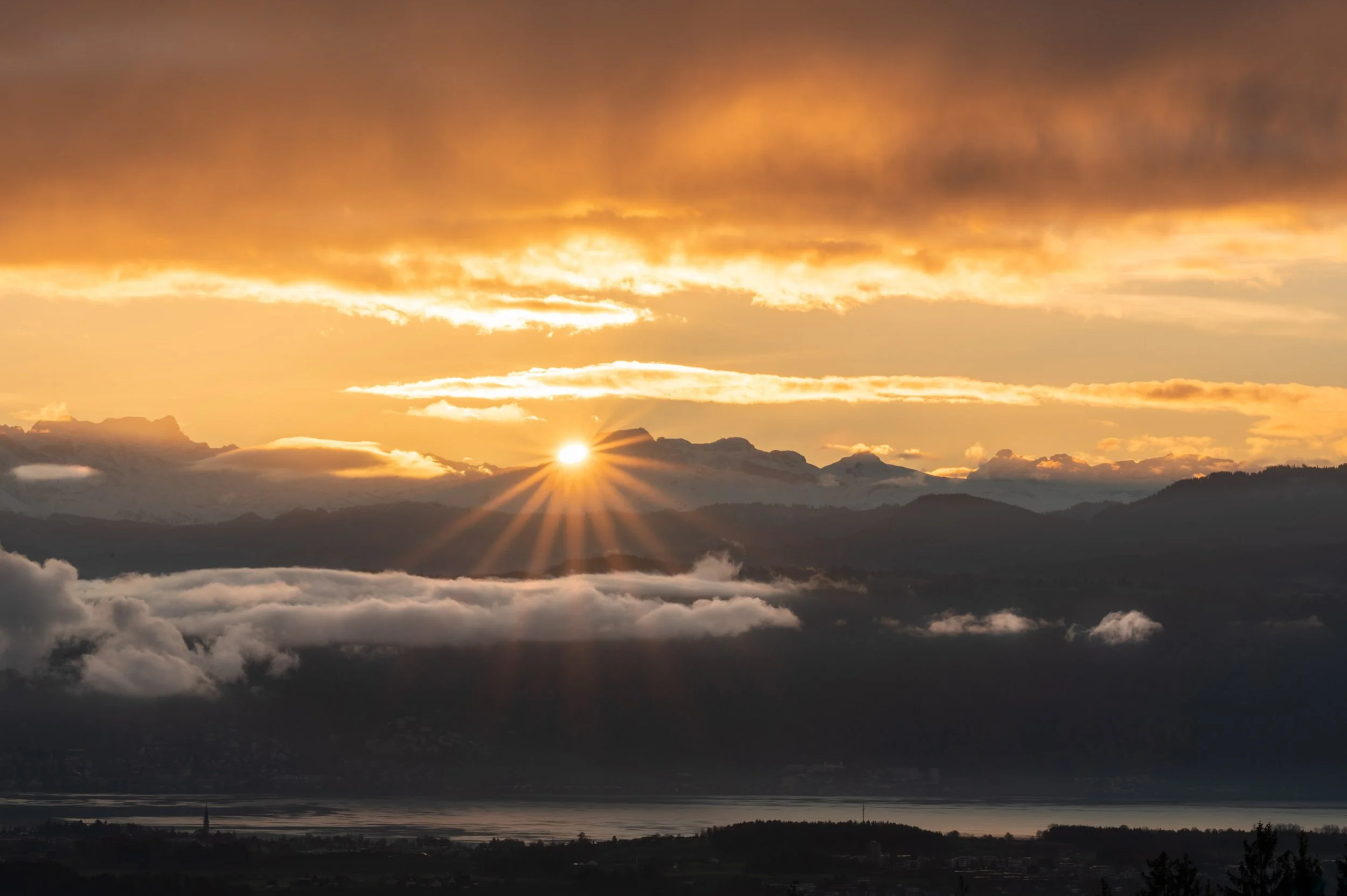 Sonnenaufgang über Bergen mit Wolken und Sonnenstrahlen