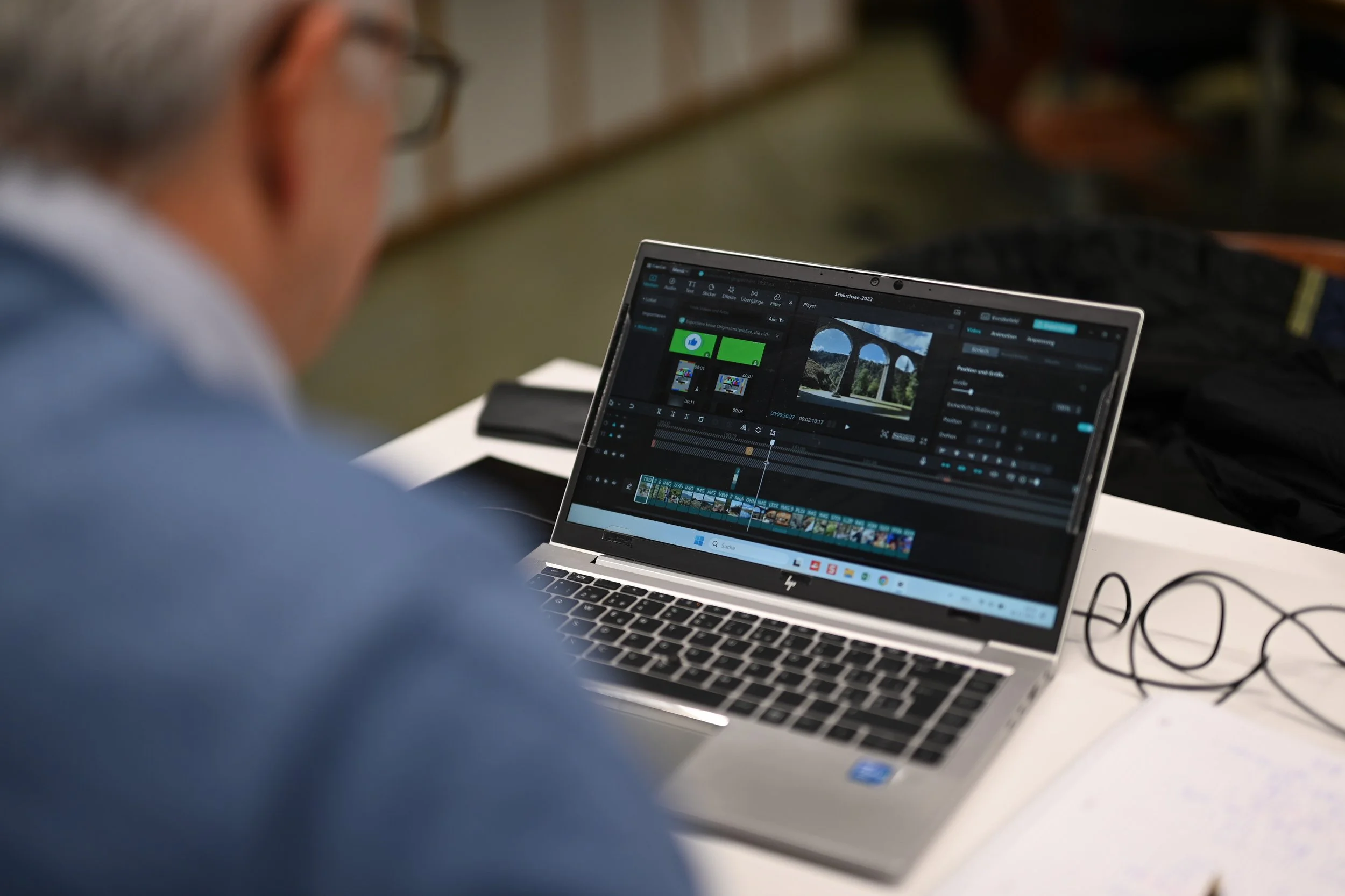 Nahaufnahme eines Mannes, der an einem Laptop arbeitet, auf dem eine Videobearbeitungssoftware geöffnet ist.