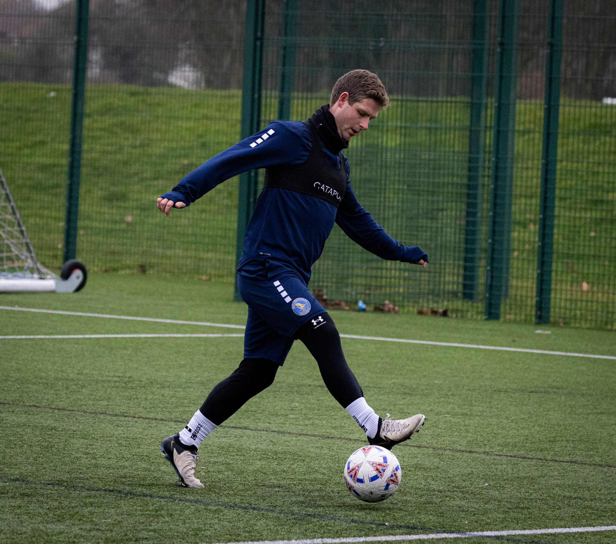 A man playing soccer on a field during a cloudy day.