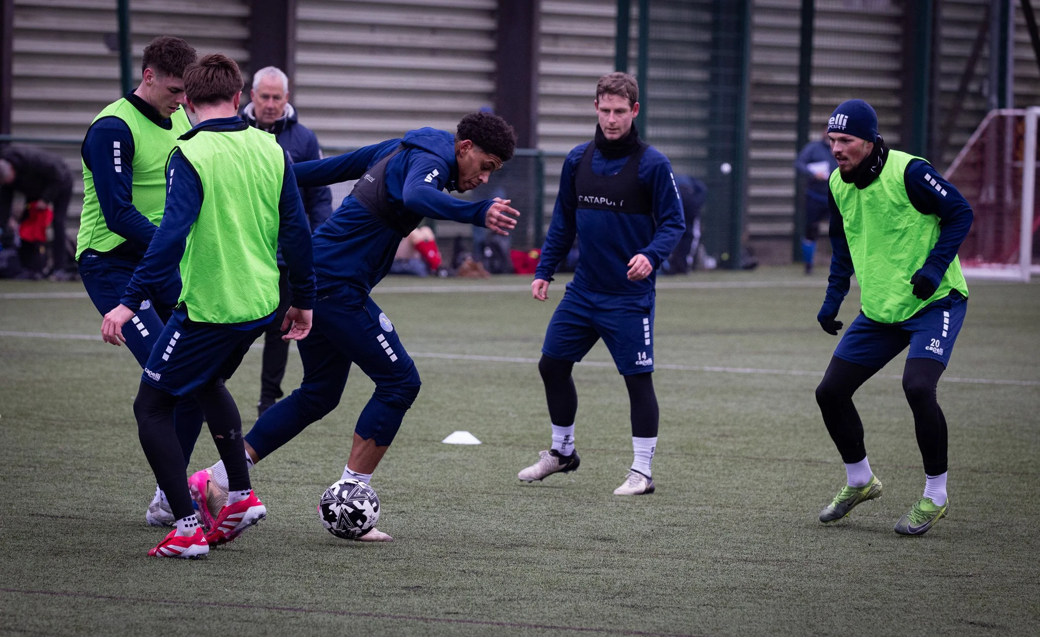 Soccer players practicing passing on an artificial turf field during a training session.