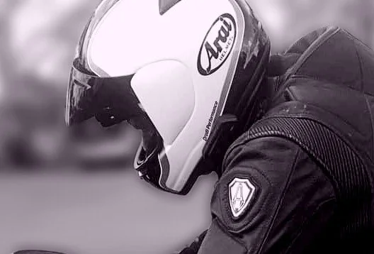 Close-up of a motorcyclist wearing a full-face helmet and riding gear.