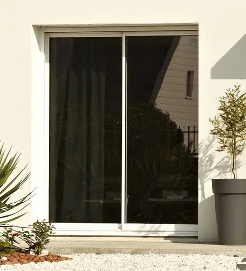 Fenêtre coulissante à double volet dans un bâtiment moderne, avec des plantes en pot à côté.