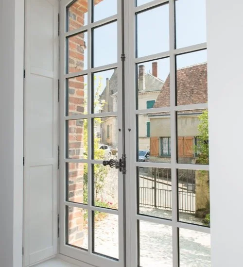 Fenêtre à carreaux avec vue sur des maisons et la rue extérieure.