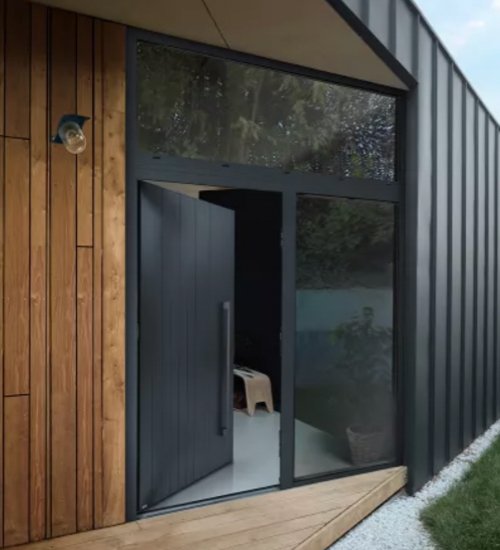 Une porte en verre noire avec une section en bois, une petite chaise à l'intérieur, et une pièce d'éclairage à l'extérieur.