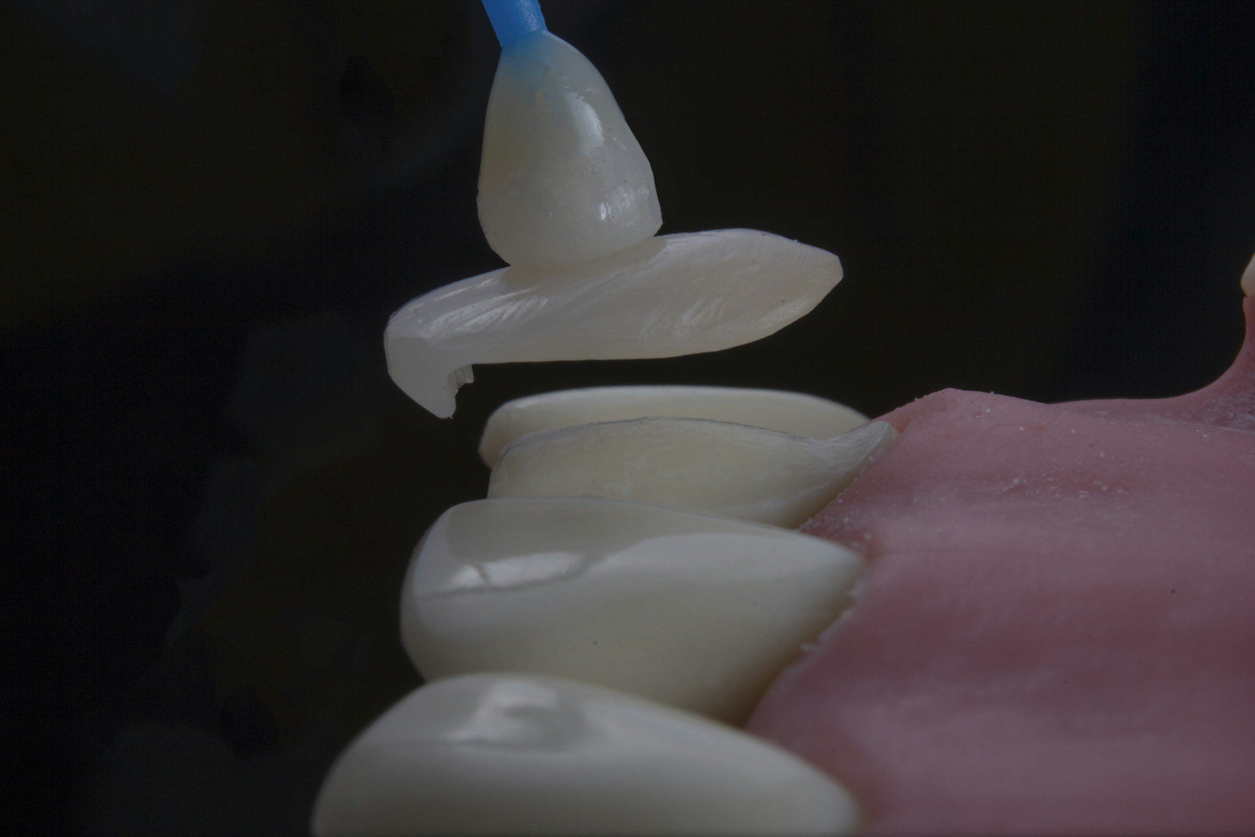 Aplicação de creme branco na superfície de um consumível rosa, usando um tubo de aplicação.