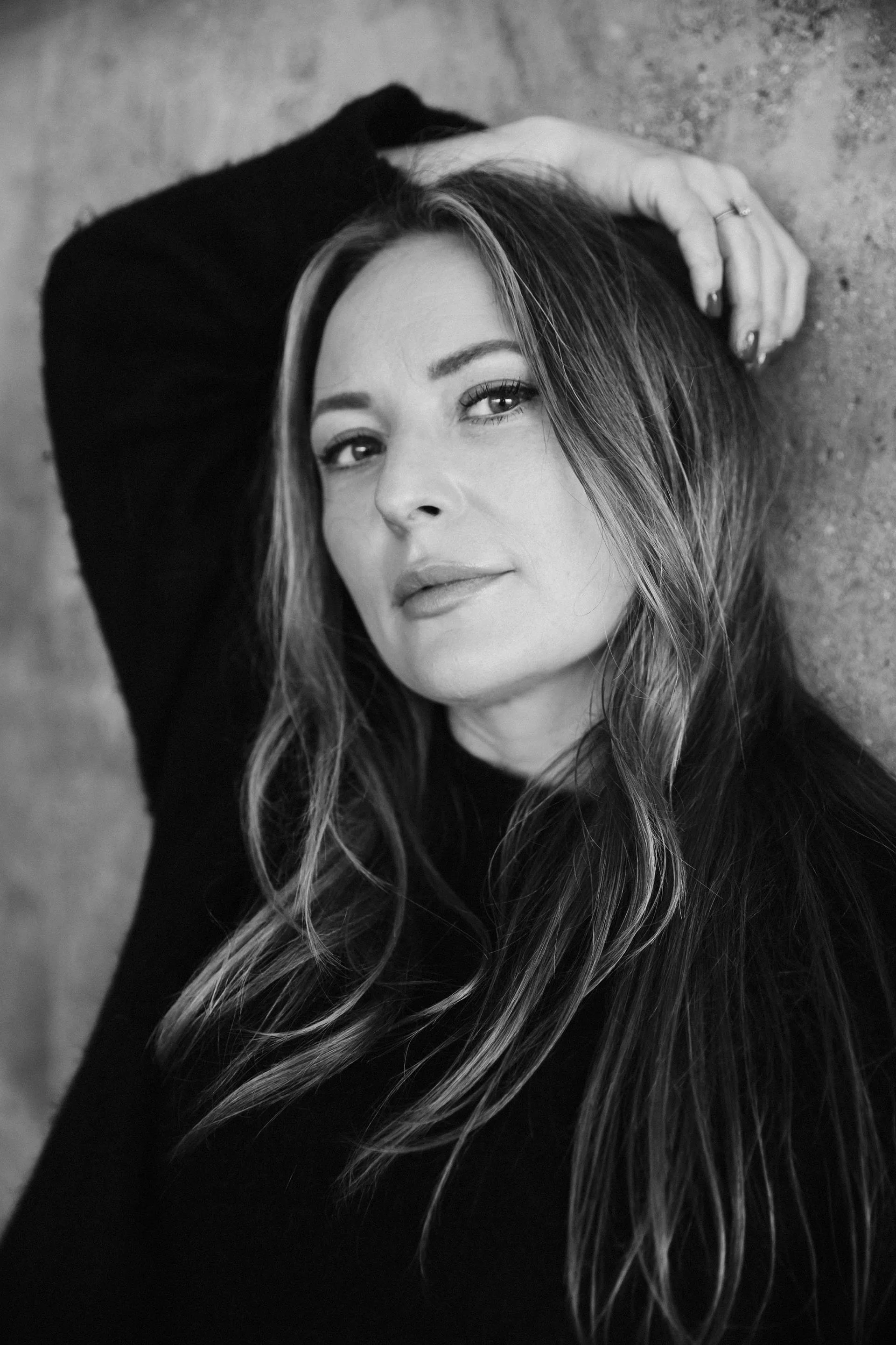 Porträtt av en kvinna (Emelie från musikquizz)  med långt, vågigt hår som lägger huvudet på marken och tittar in i kameran.