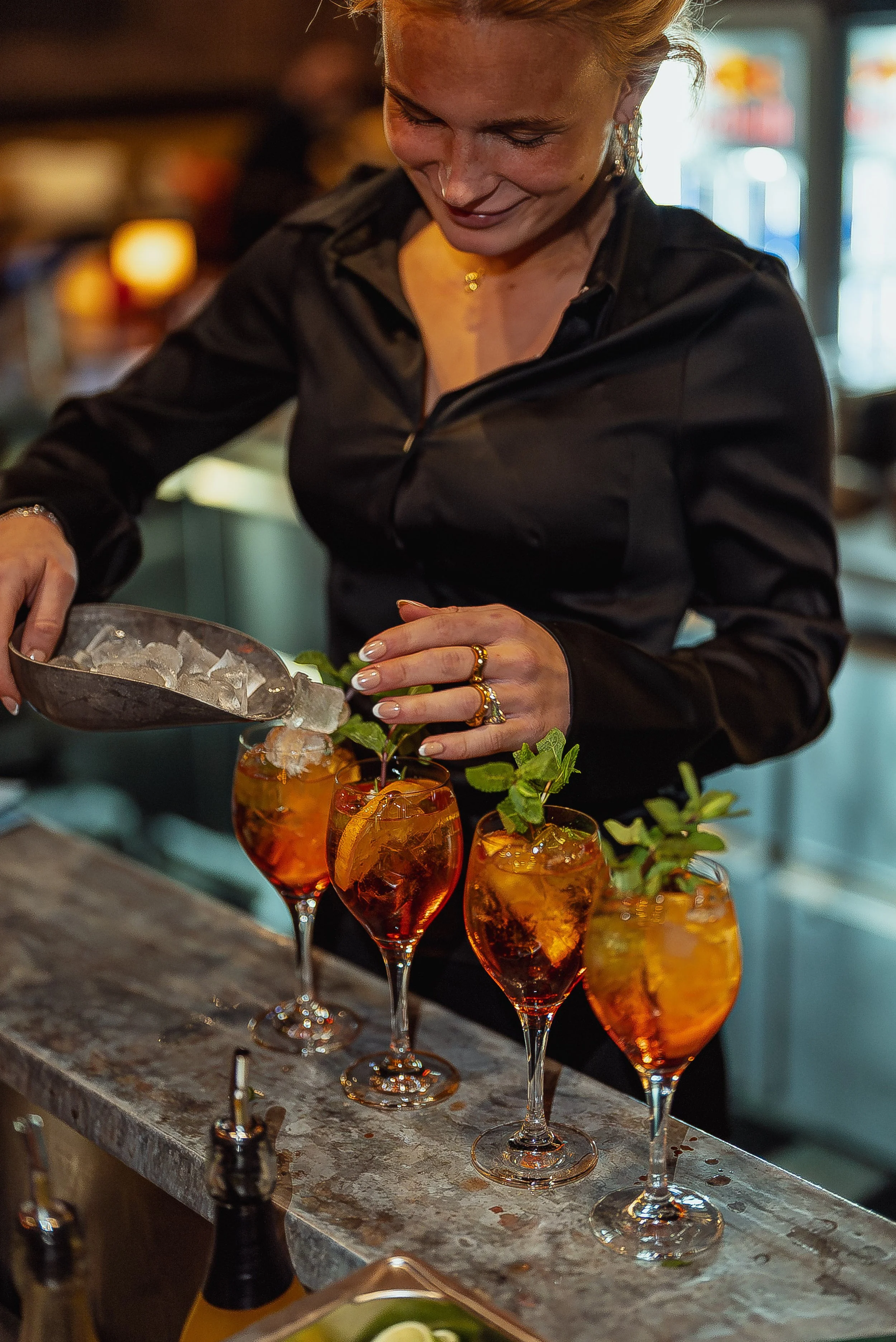 En kvinna gör cocktails med is i en bar.