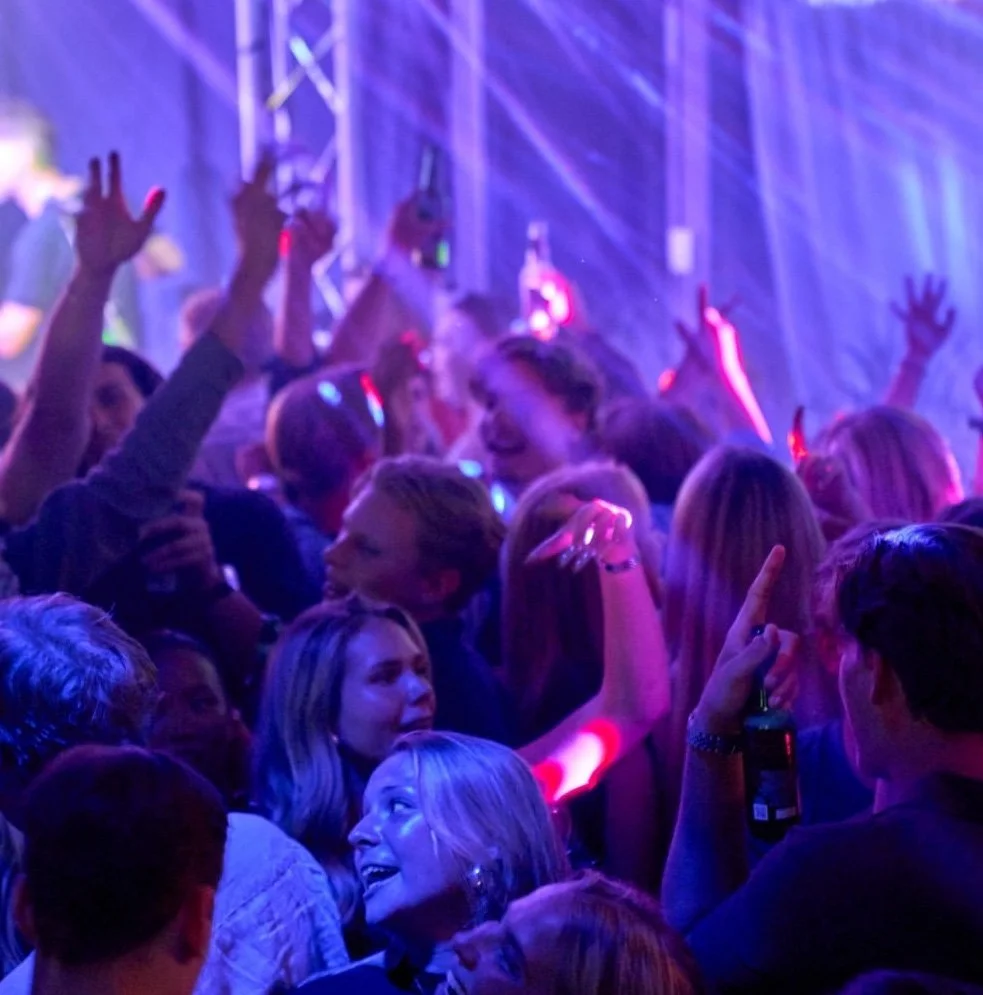 Folk som dansar och har roligt på en nattklubb med färgstark belysning.