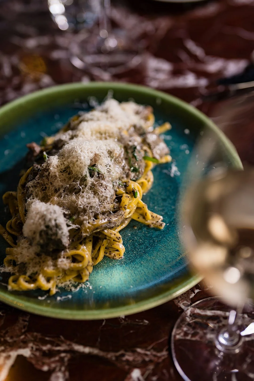 En tallrik med pasta toppad med riven ost, serverad på en grön tallrik.