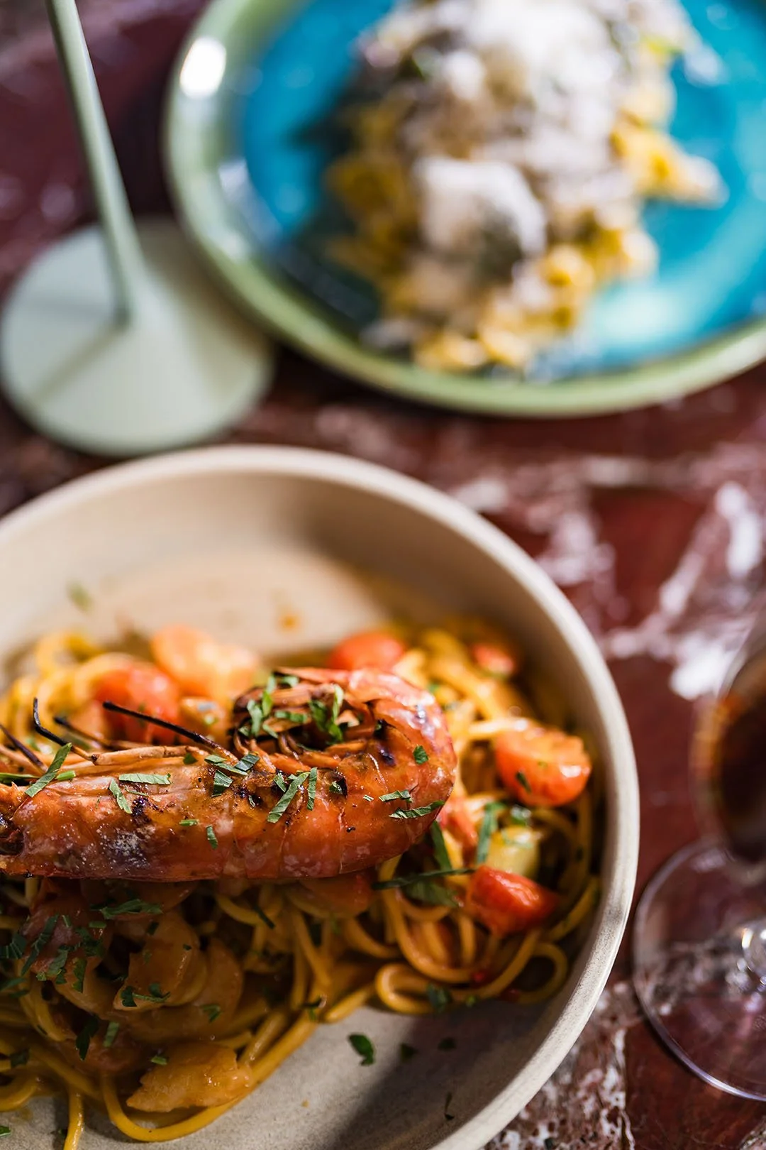 En tallrik med pasta med räkor och tomater, garnerad med hackad basilika.