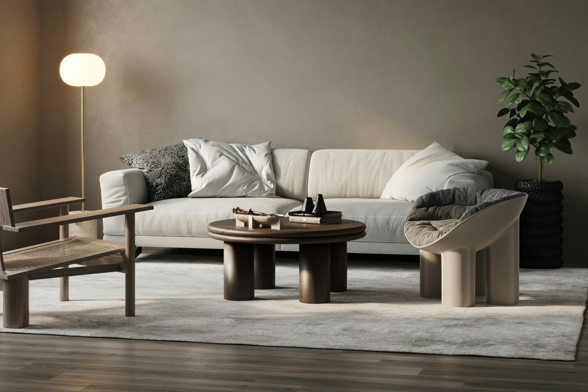 A minimalist living room with a white sofa, black and white cushions, a wooden coffee table with decorative items, a modern beige chair with a cushion, a tall potted plant, a wooden side chair, and a floor lamp, on a light gray rug.