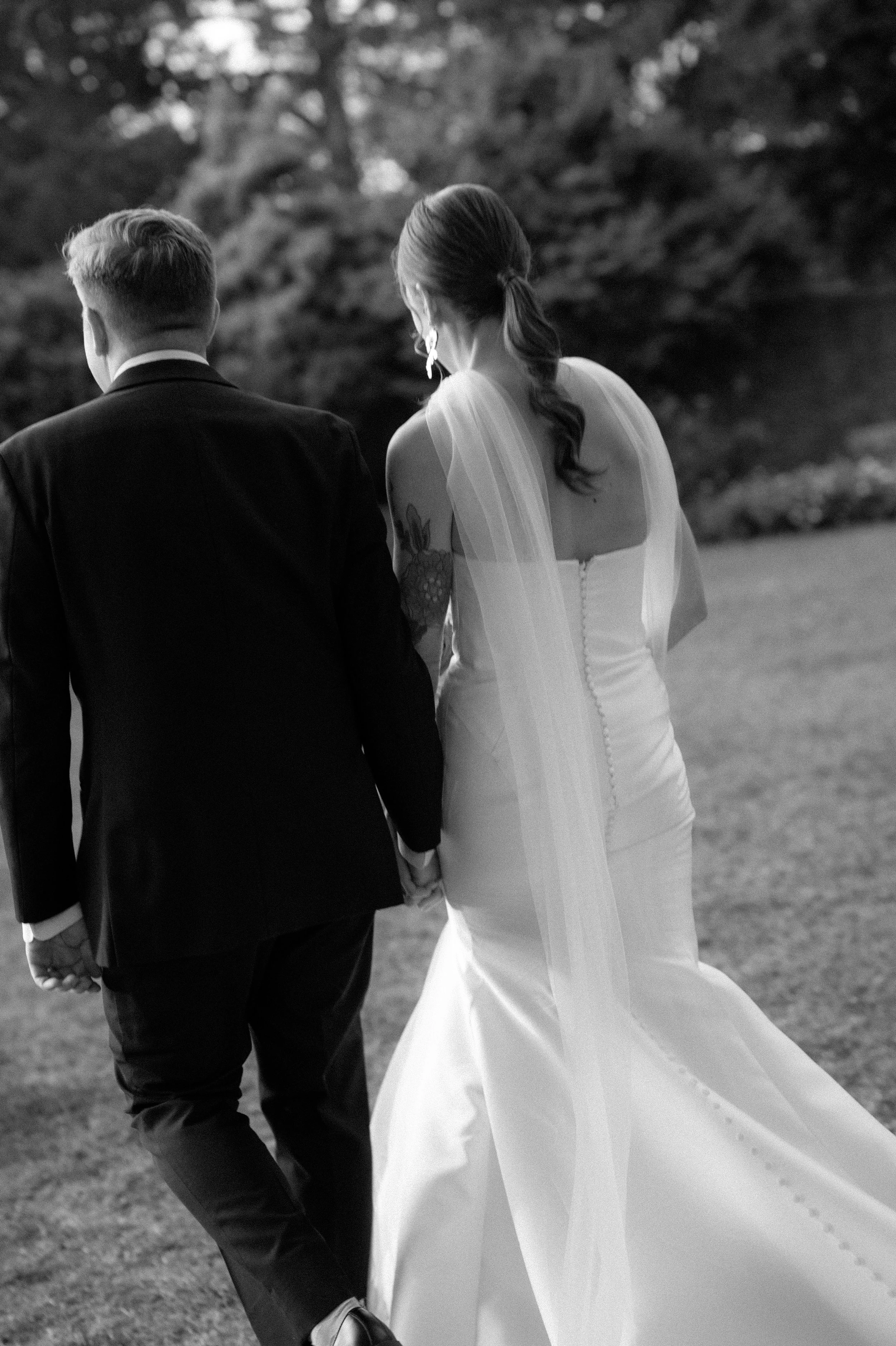 A newly-married couple walks away from the camera in black and white