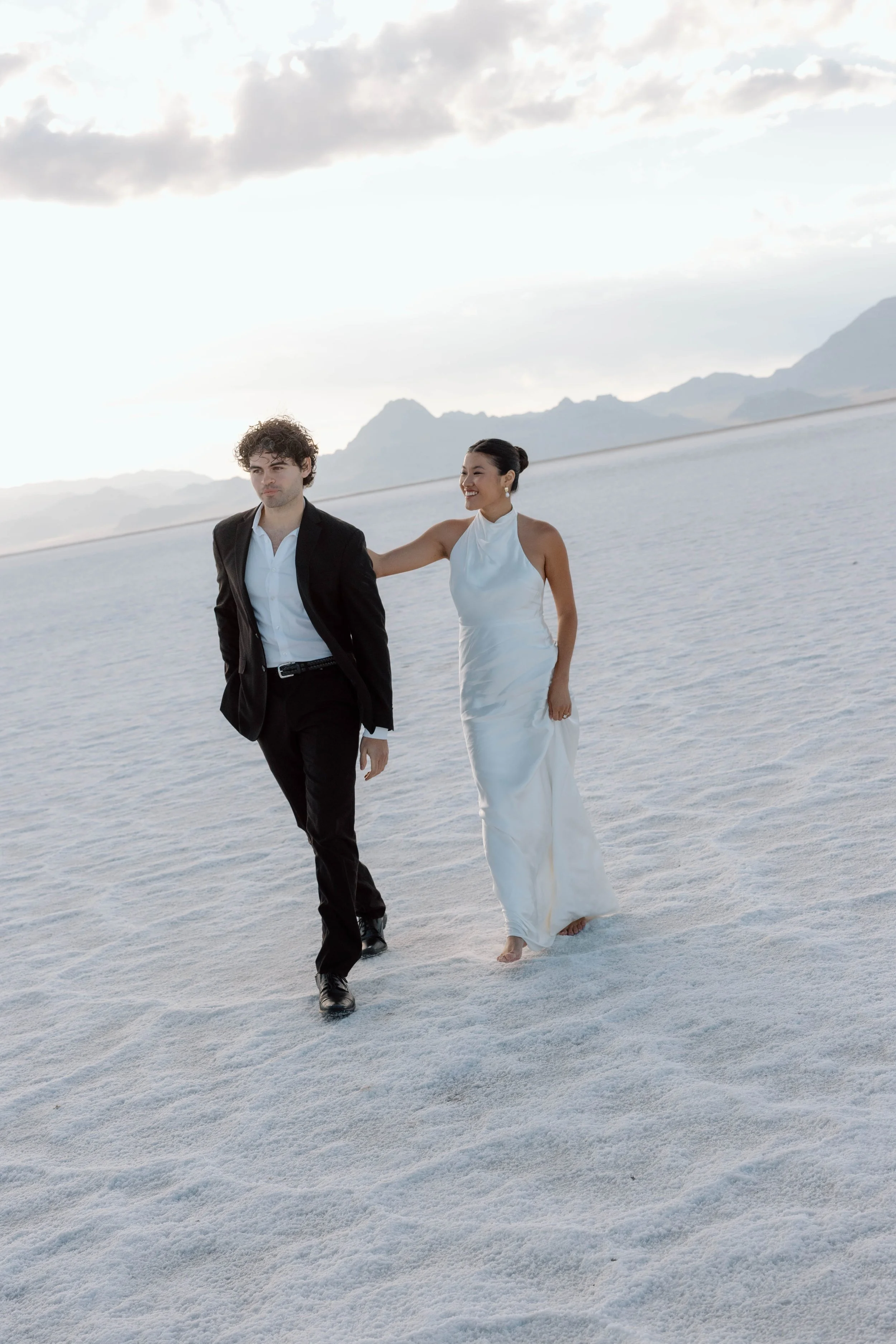 A couple walks across the Utah Salt Flats in wedding attire