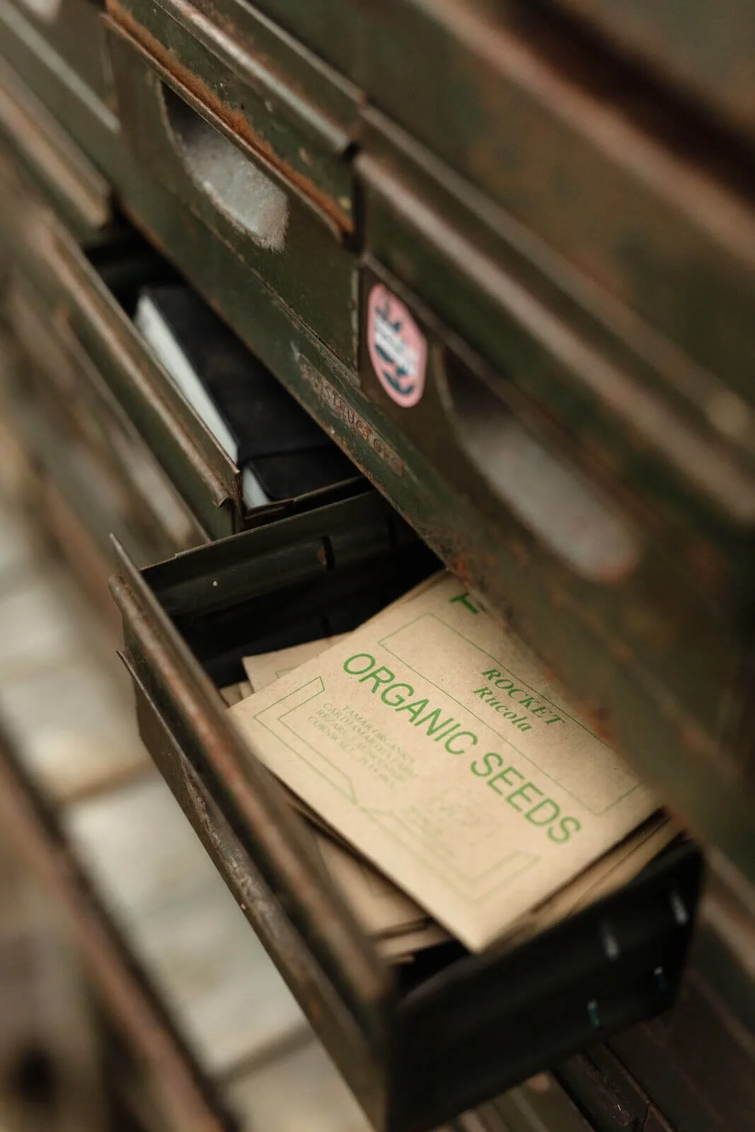 Vintage metal drawers containing organic seed packets labeled 'Rocket Rucola.'