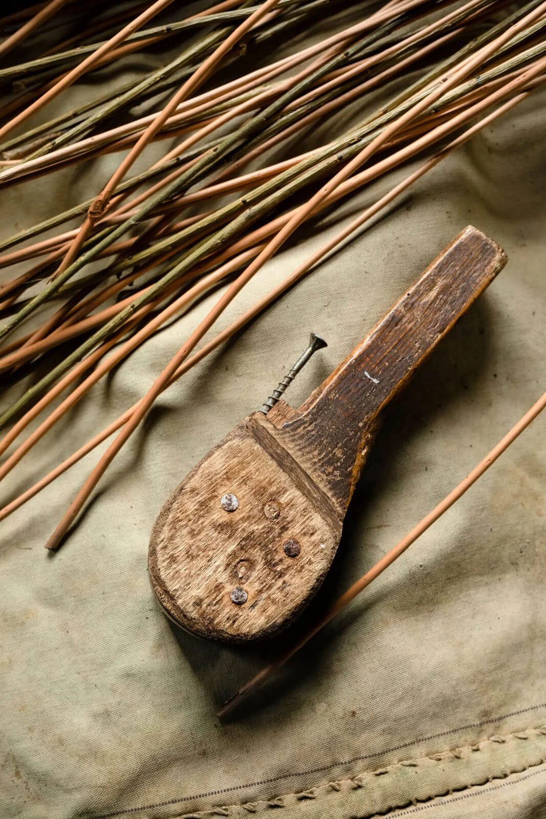 Old wooden tool on canvas with thin wooden sticks and a screw.