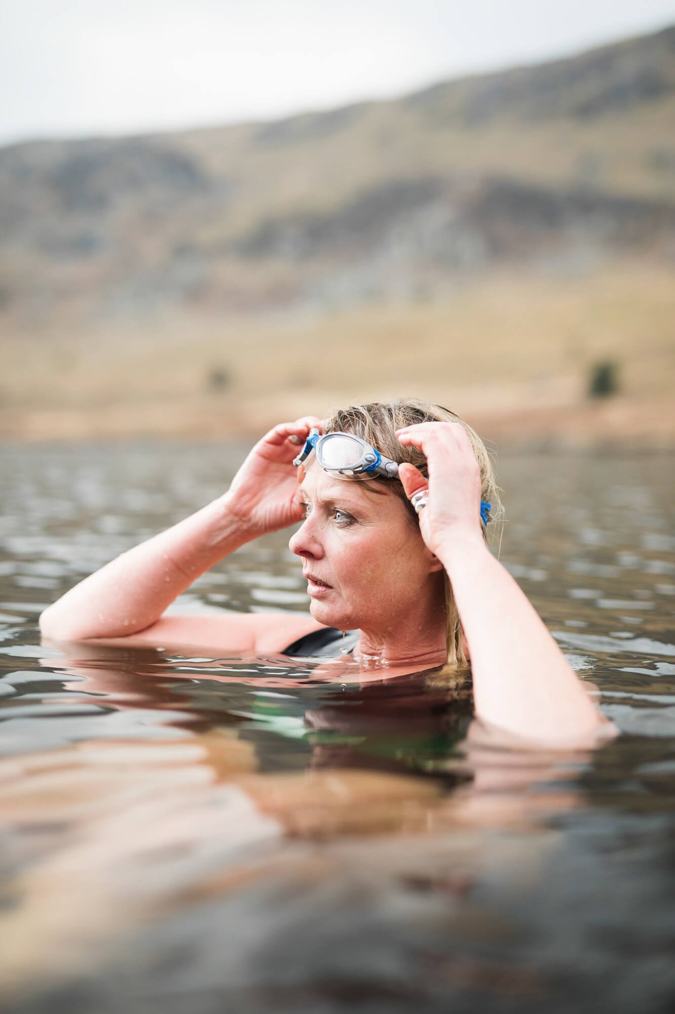 Woman adjusting swim goggles while swimming in a lake
