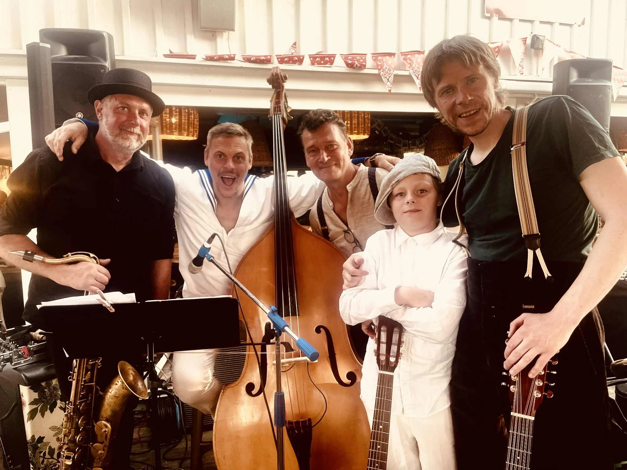 En person spelar gitarr utomhus vid solnedgången, med en träbord och ett glas i bakgrunden.