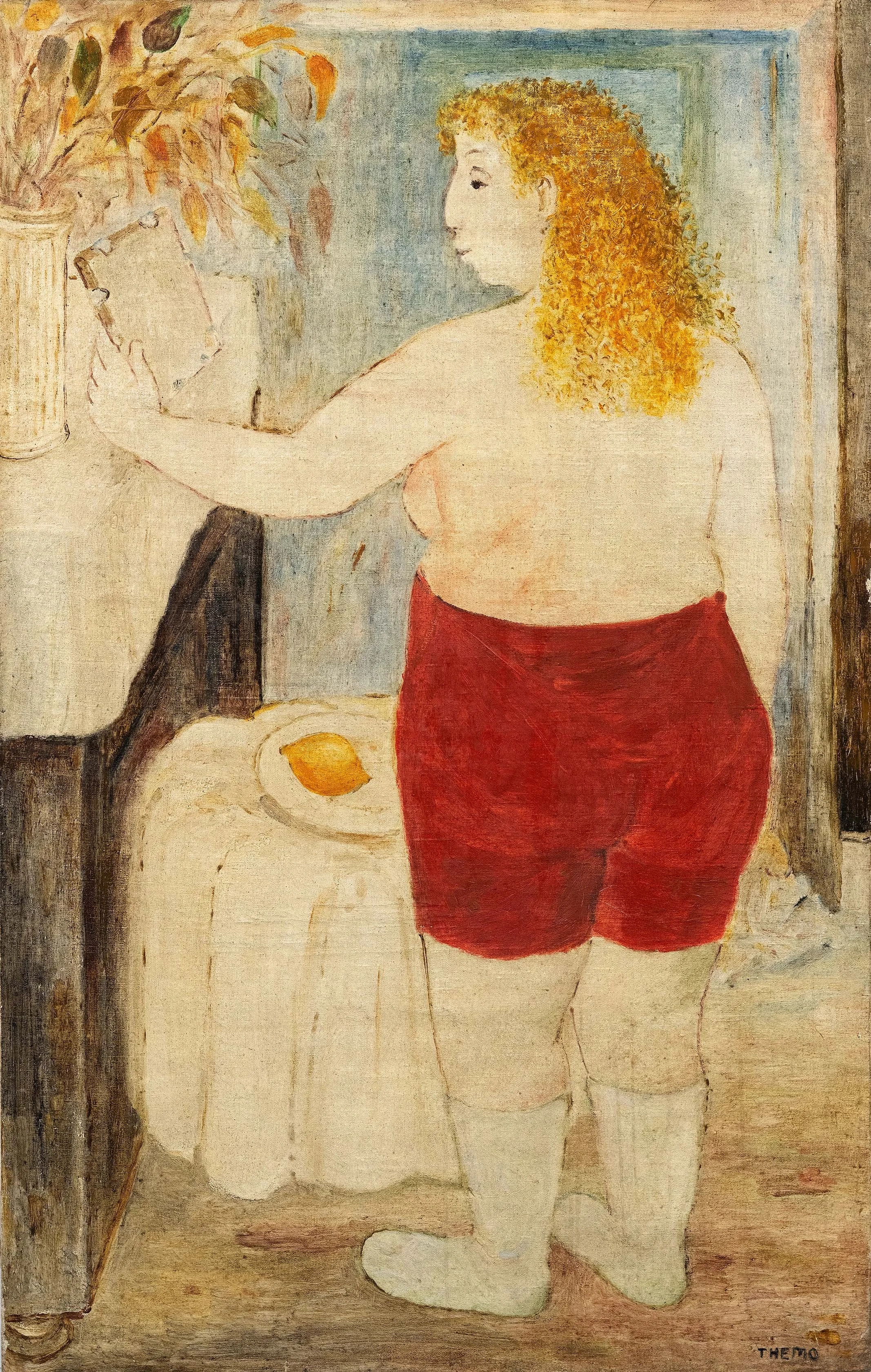 A woman with curly red hair and fair skin, wearing red shorts, is painting a flower on a canvas. She is kneeling on the floor with her back to the viewer, with her right arm extended and holding a brush. A large potted plant with green and orange leaves is on the table beside her, and a lemon on a plate is also on the table.