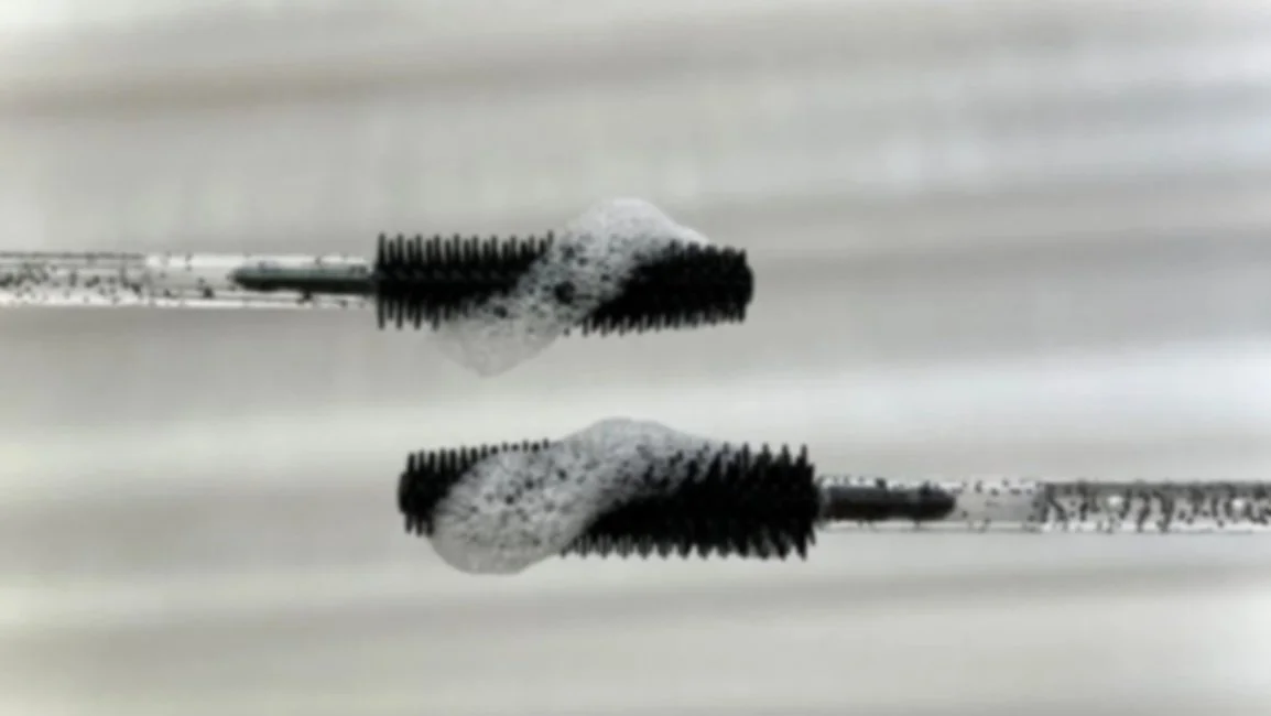 Close-up of a metal screw with a washer, reflected in a smooth metallic surface.