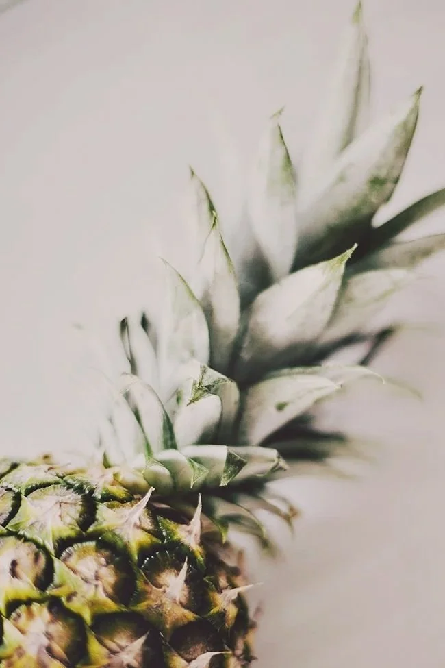 Close-up of the top part of a pineapple showing its spiky leaves.