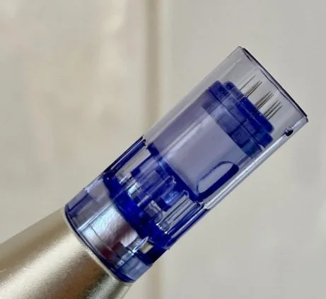 Close-up of a transparent blue ink cartridge or container on a metallic surface.
