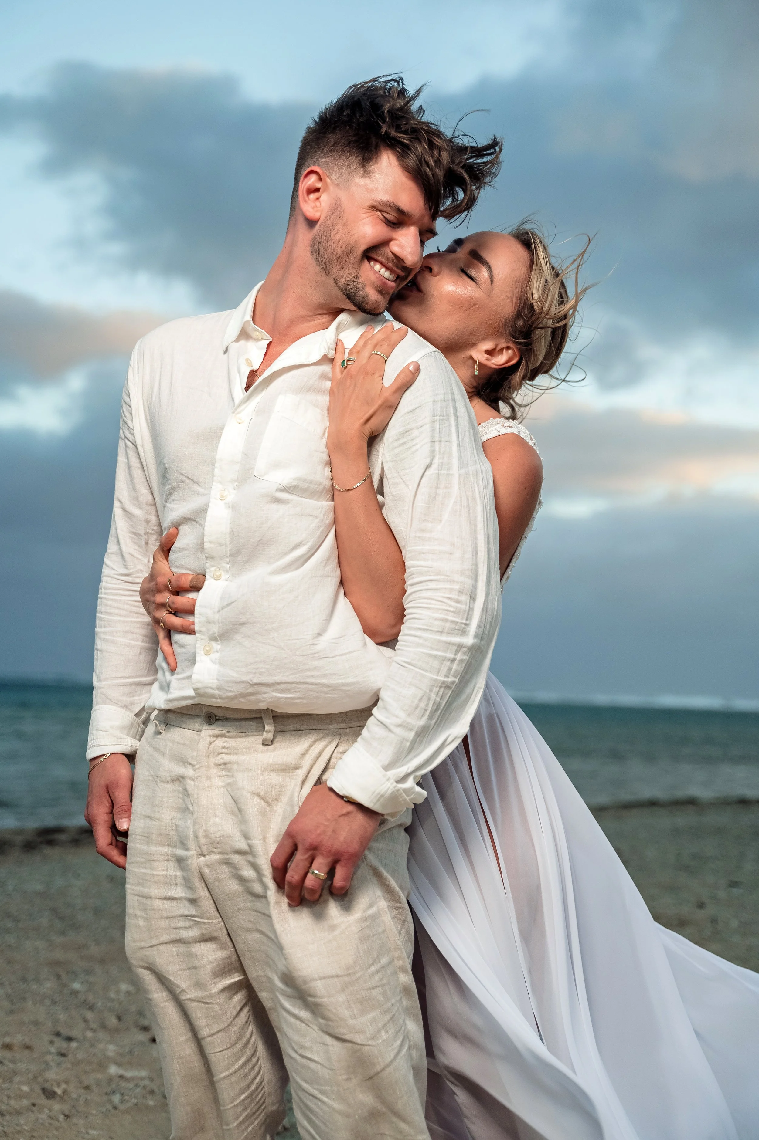 A happy couple embracing on the beach at sunset.