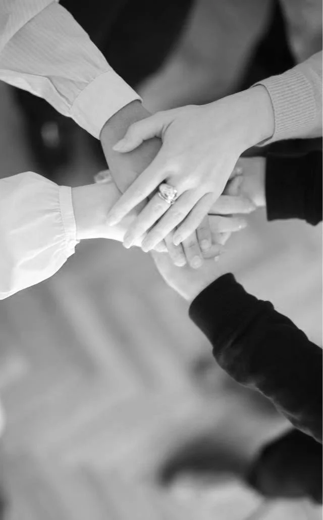 Multiple hands stacked together, showing unity and teamwork.