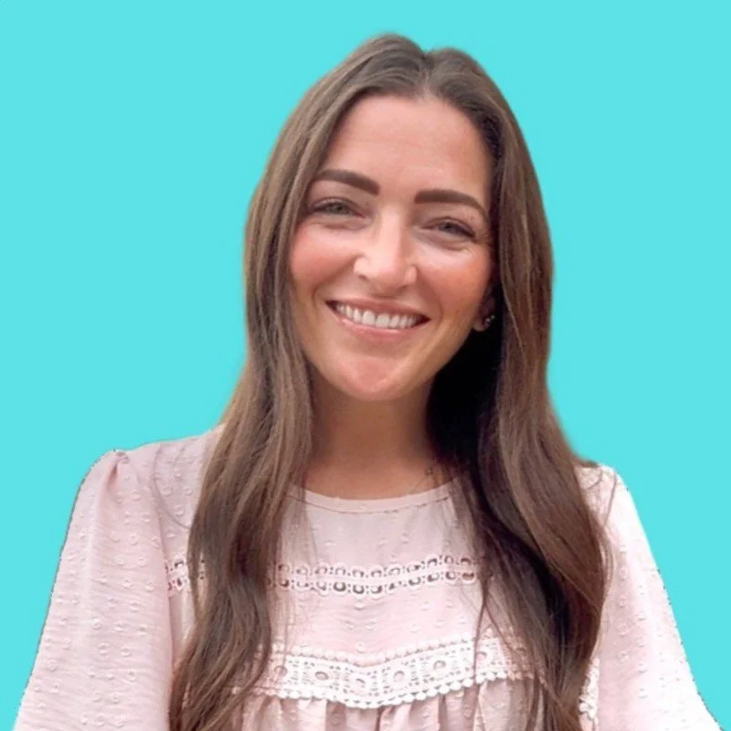 A woman with long brown hair smiling against a light blue background.