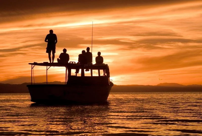 Guests enjoy a sundowner cruise on Lake Malawi, with golden light reflecting across the lake’s pristine waters.