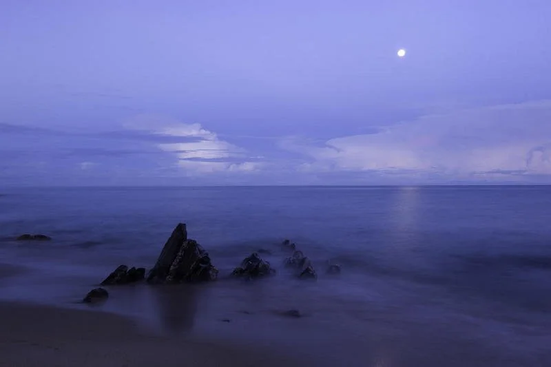 A full moon illuminates the northern lakeshore of Lake Malawi, casting a serene glow over the water.