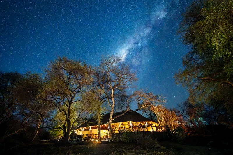 Thatch safari lodge at night under the Milky Way in Malawi