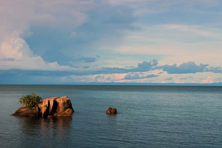 A small rocky island in Lake Malawi surrounded by clear freshwater.