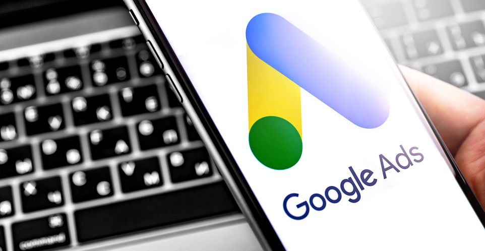 Téléphone portable affichant le logo de Google Ads, à côté d'un clavier d'ordinateur.
