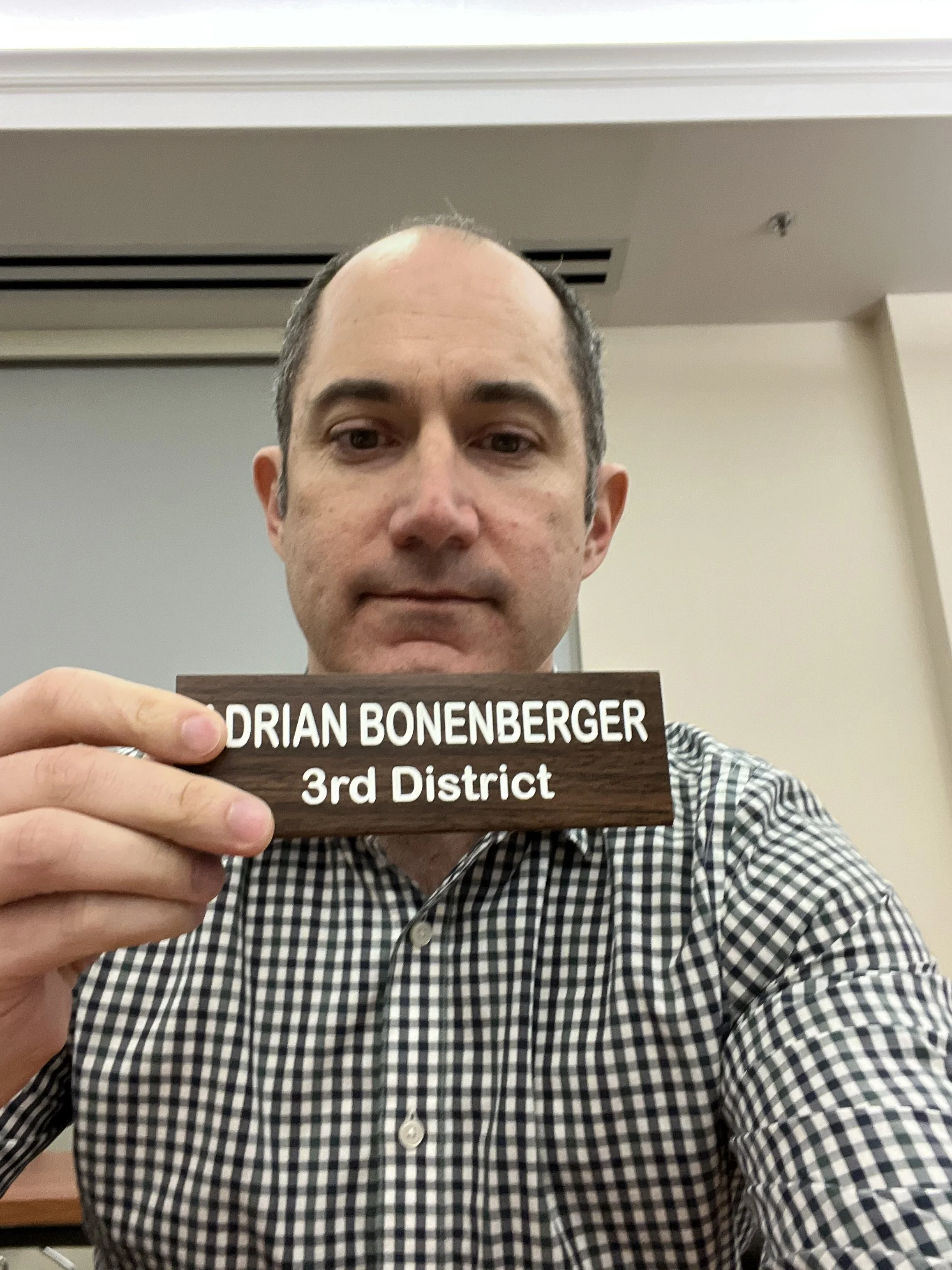 Adrian Bonenberger holds a nameplate from his time on the Branford RTM that reads 'ADRIAN BONENBERGER 3rd District'.