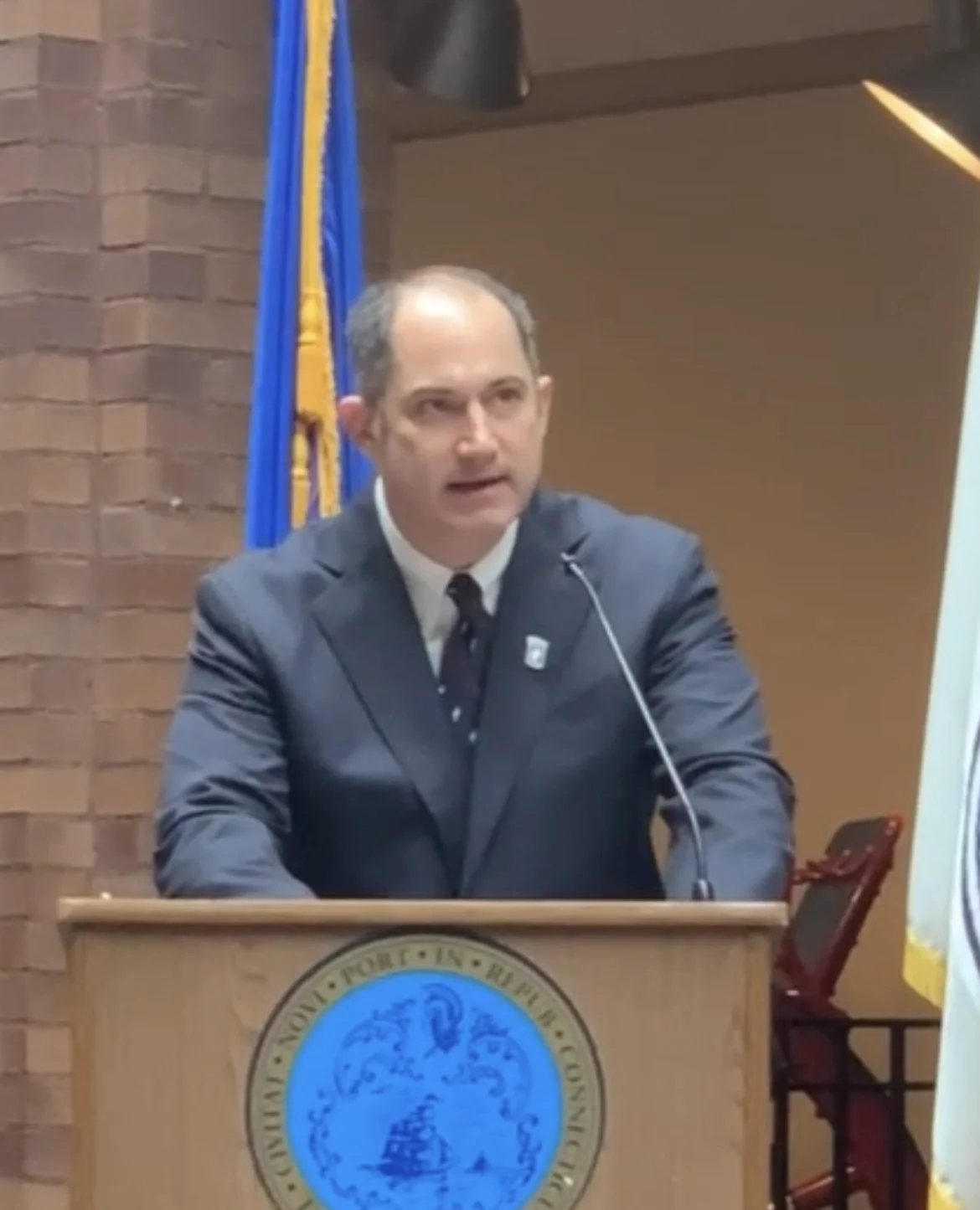Adrian Bonenberger in a charcoal suit by J Press speaking at New Haven's Veterans Day ceremony in 2022..