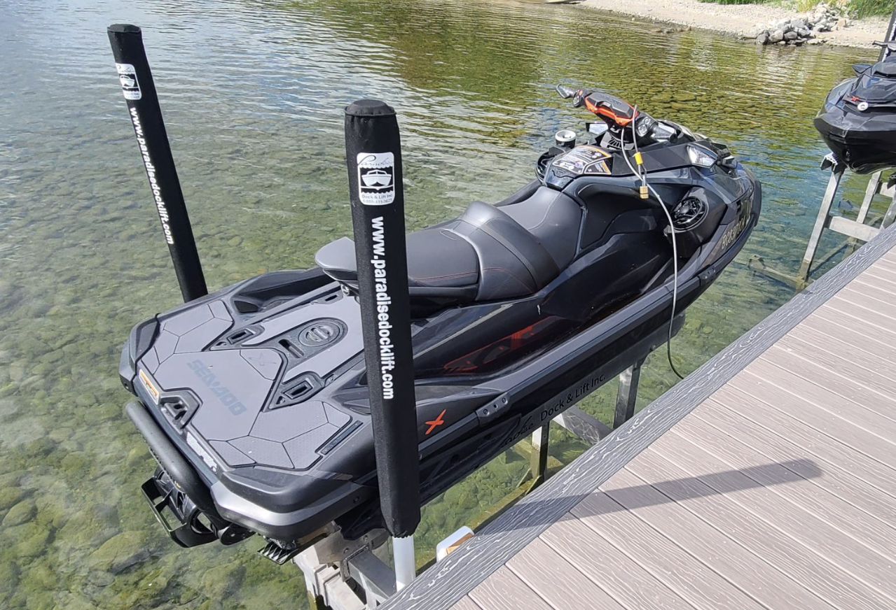 A black jet ski docked next to a wooden dock on clear water