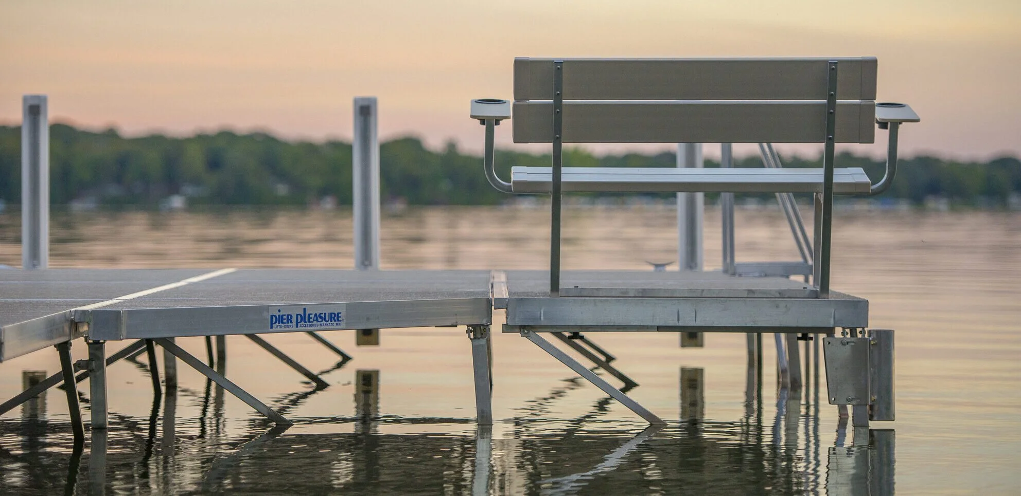 Empty pier with a bench overlooking a calm body of water during sunset.