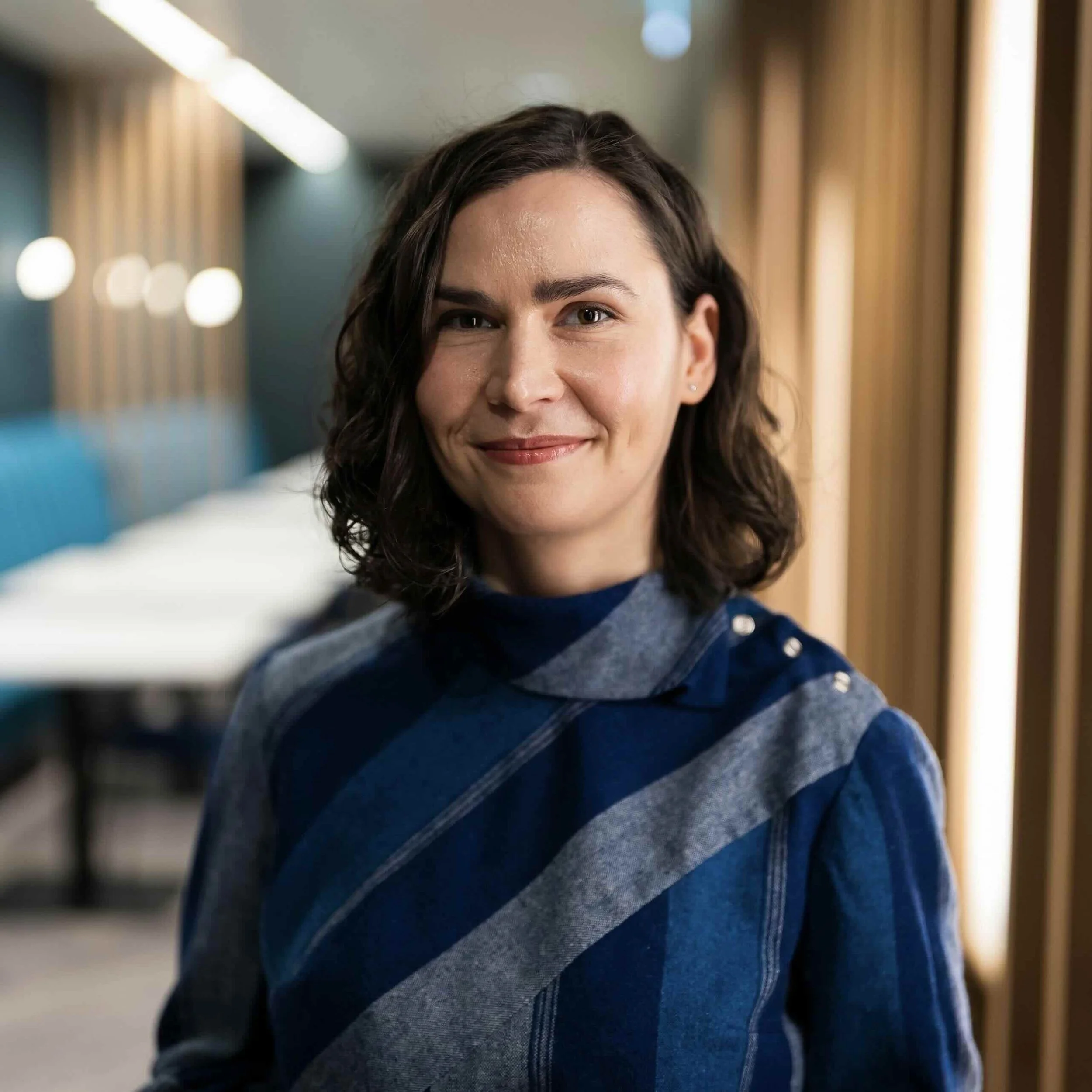 Professional portrait of psychologist Mihaela Calin smiling warmly, representing her approachable and expert therapy practice in Amsterdam.