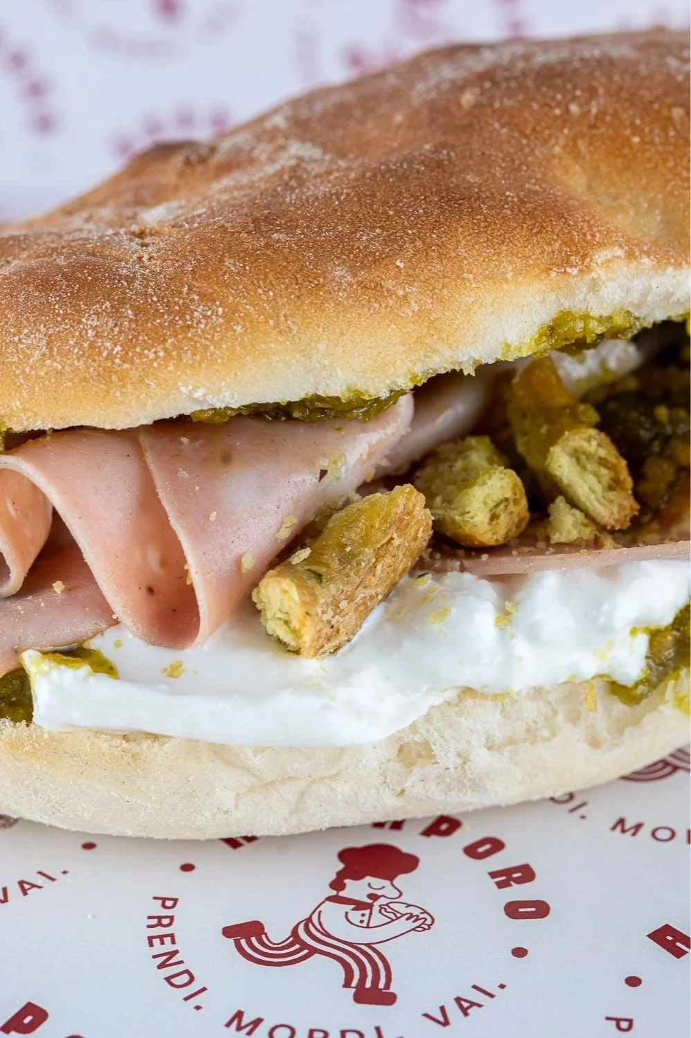 Panino con mortadella, burrata, pesto di pistacchi e taralli.