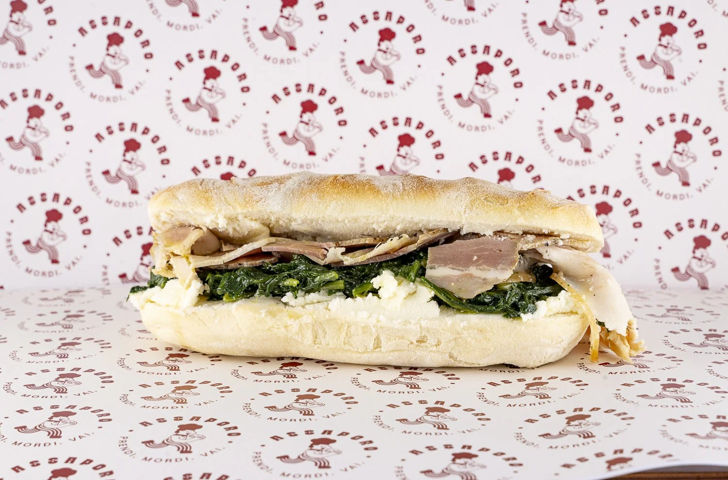 Panino con porchetta, cicoria e crema di pecorino.