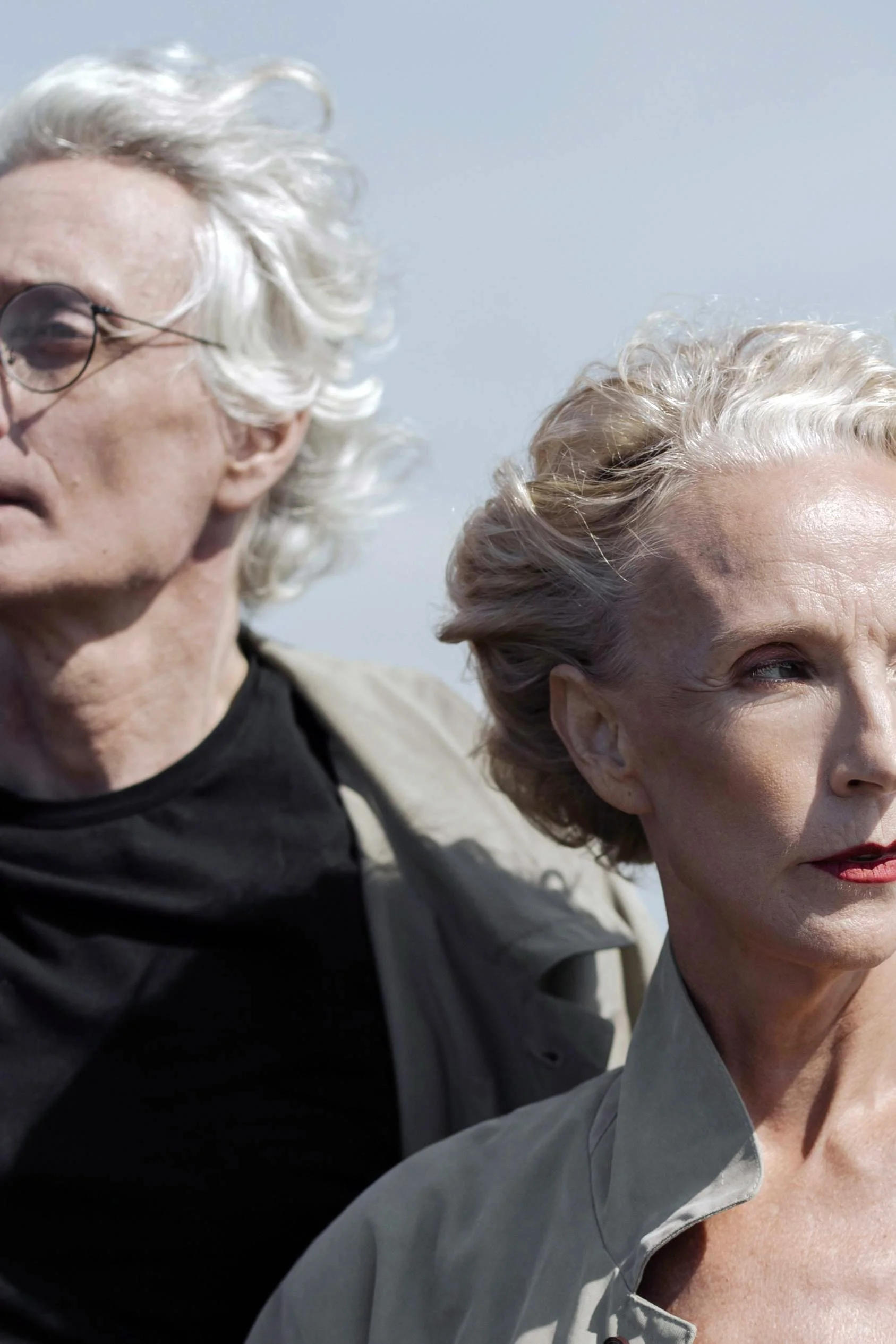Close portrait of a man and a woman standing side by side outdoors looking in different directions.