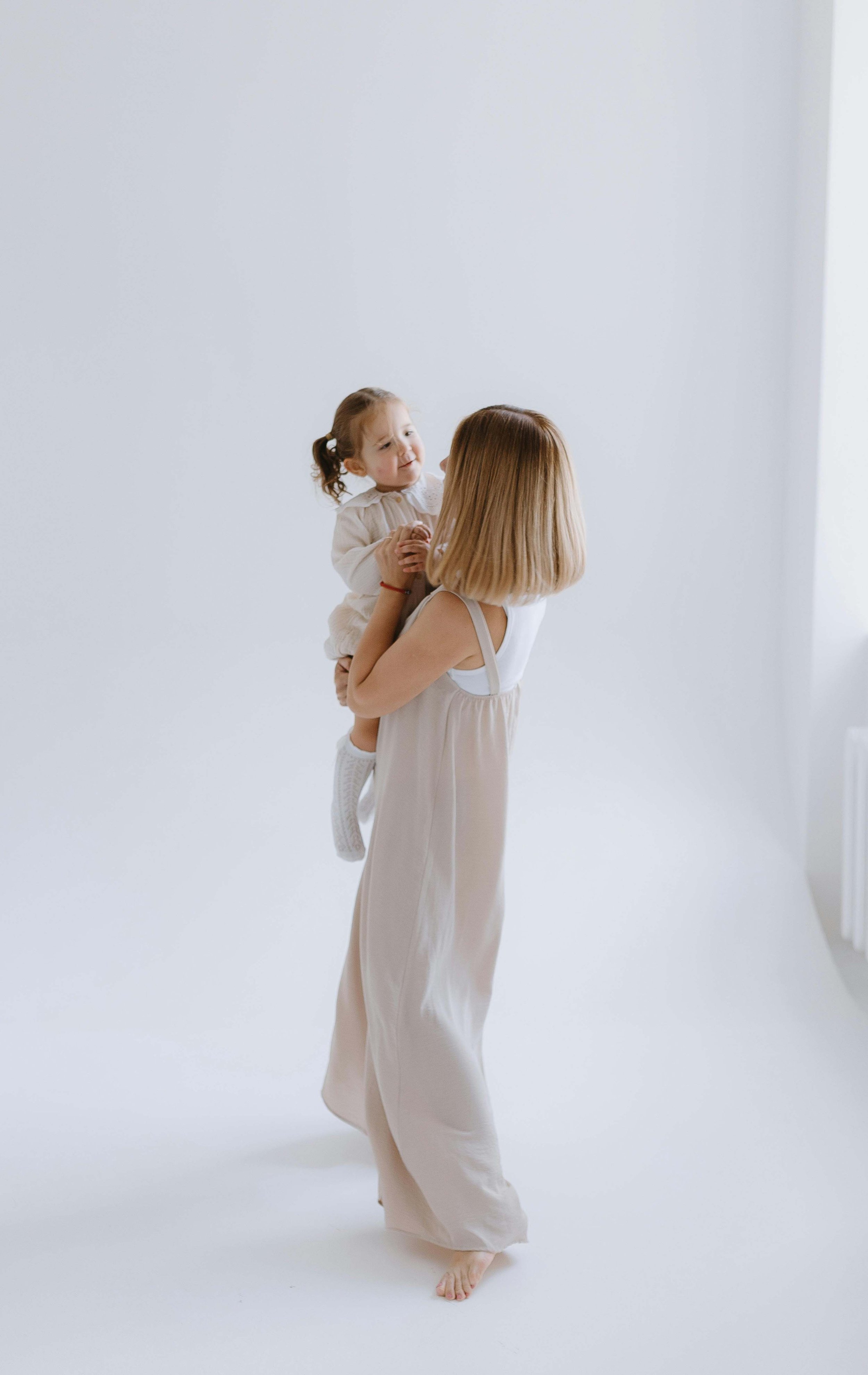 Woman holding a young child in a bright minimalist studio space.
