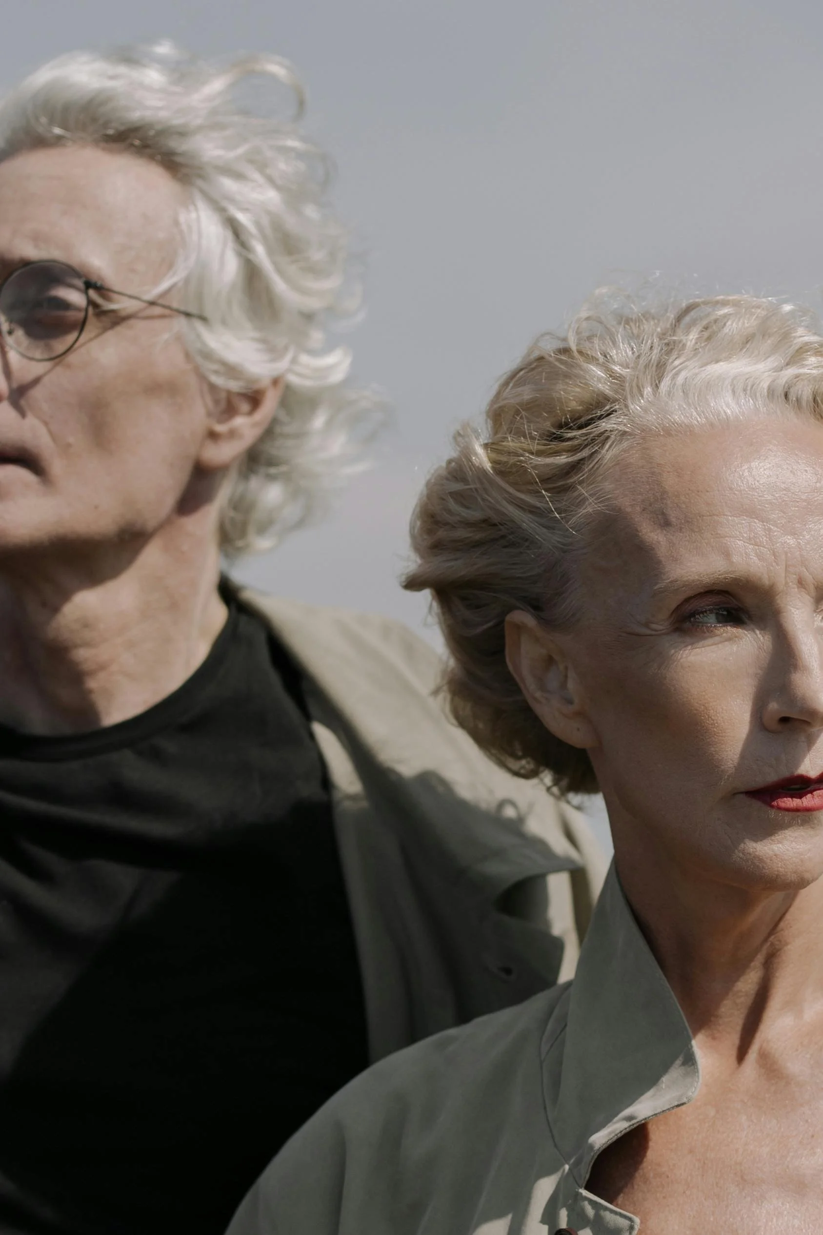 Close portrait of a man and a woman standing side by side outdoors looking in different directions.