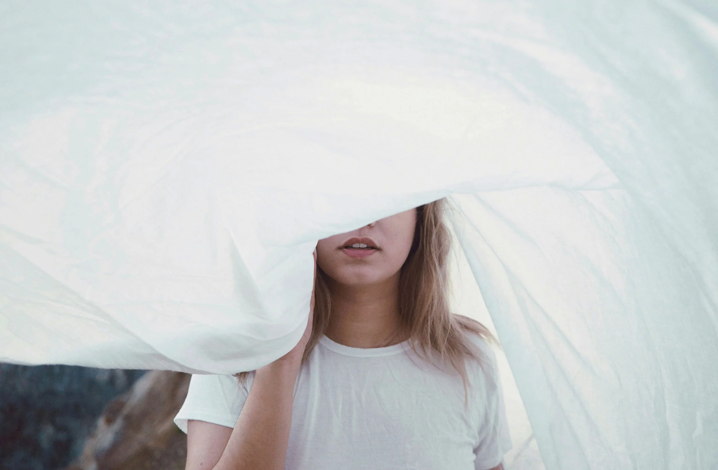 Portrait of a teen girl partially covered by flowing translucent fabric.