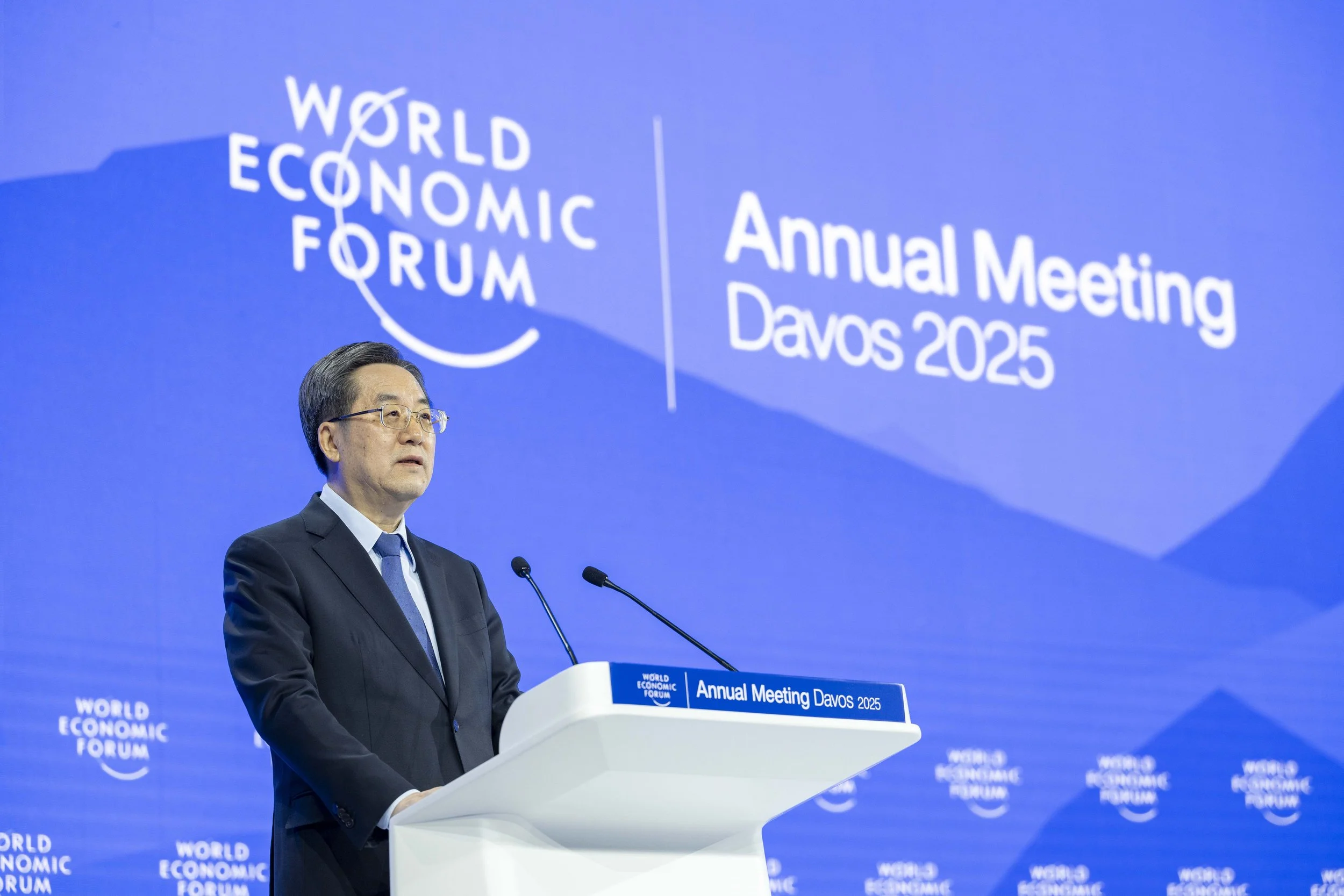 Un homme en costume parle au podium lors de la réunion annuelle du Forum Économique Mondial à Davos en 2025, avec un grand écran en arrière-plan affichant le logo du forum et le texte « Annual Meeting Davos 2025 ».