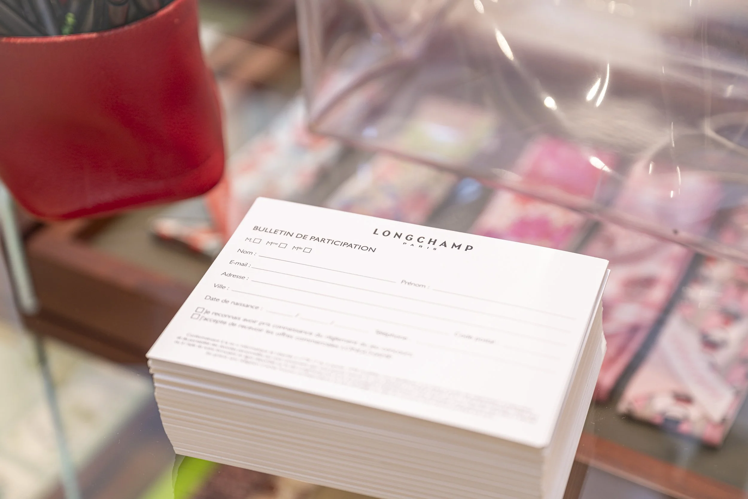 Formulaire de participation à Longchamp Paris, posé sur une table avec un fond de produits de beauté ou maquillage.