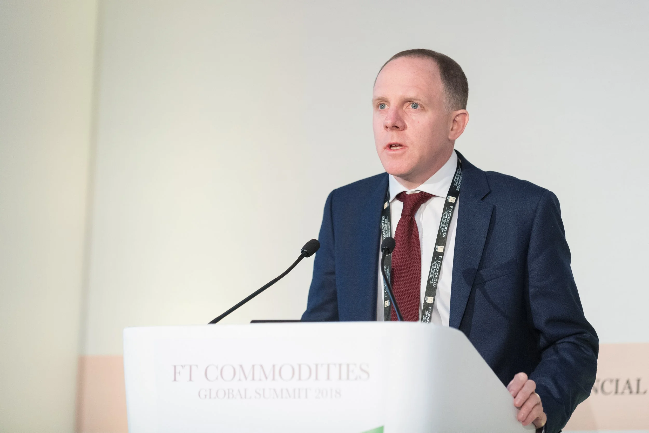 Homme en costume parlant lors d'une conférence, devant un pupitre avec inscription "FT COMMODITIES".