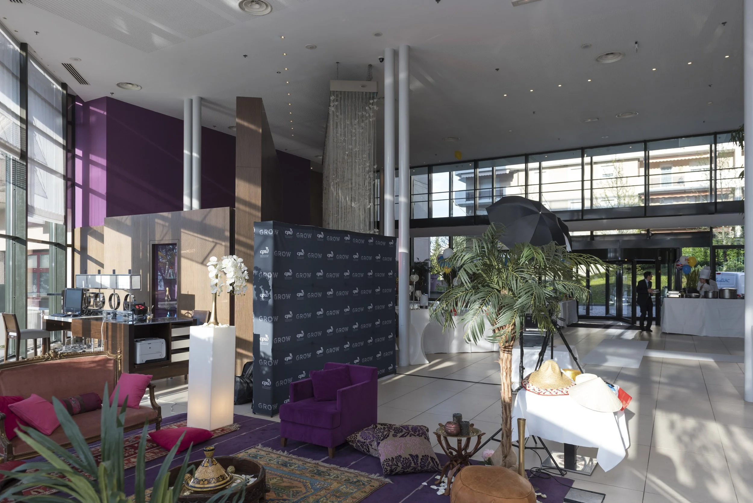 Salle d'accueil lumineuse avec mobilier coloré, plantes, et un espace avec un panneau de bienvenue 'GROW' en arrière-plan, dans un bâtiment moderne.