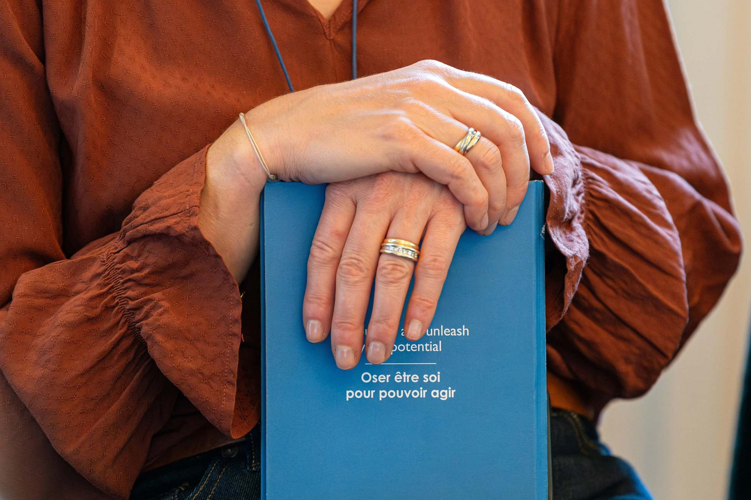 Mains posées sur un livre bleu portant un message en français sur l'authenticité et l'action.