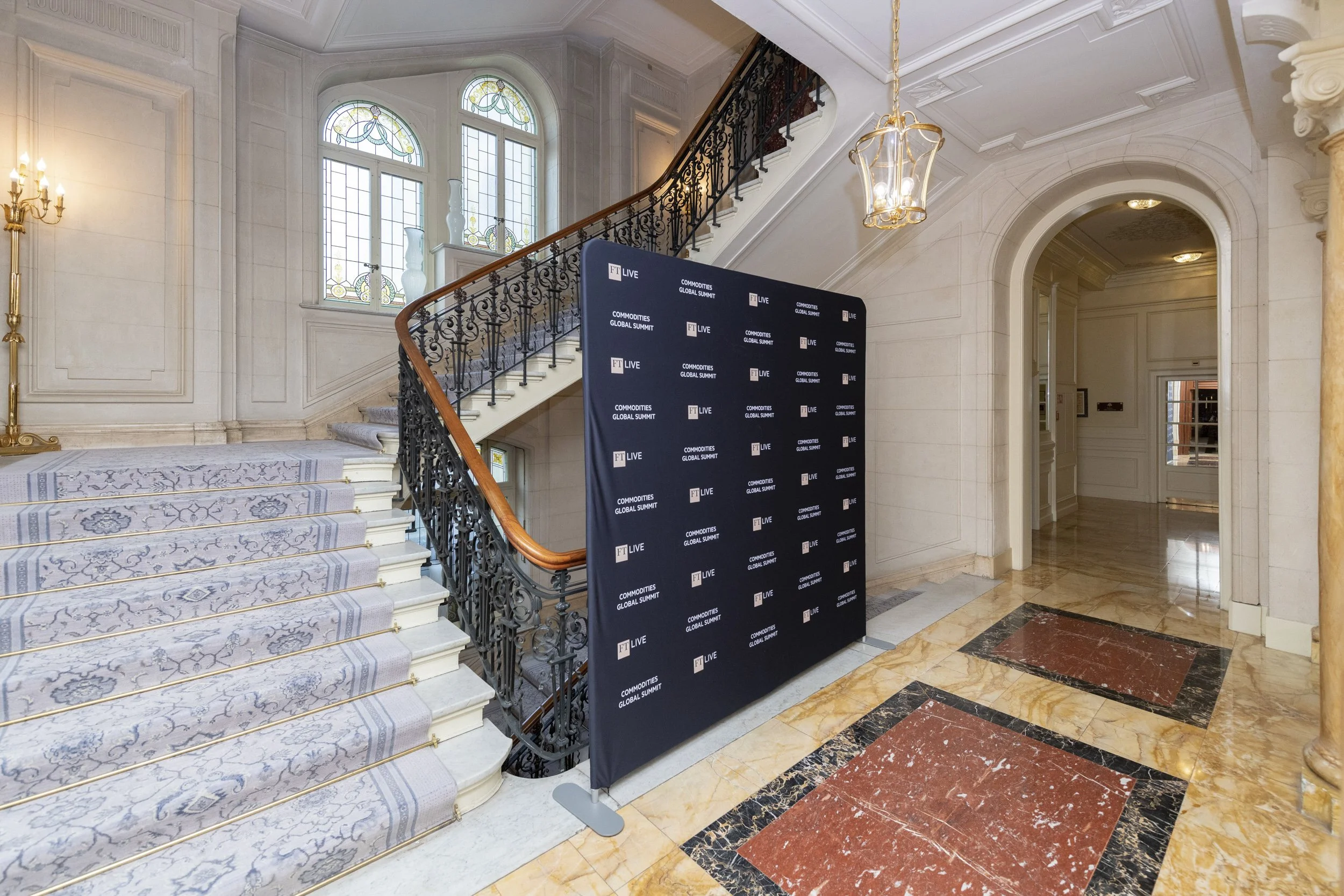 Intérieur d'un bâtiment élégant avec une grande cour intérieure, escaliers en marbre, vitraux, mur blanc, plancher en marbre, une bannière noire pour un sommet économique.